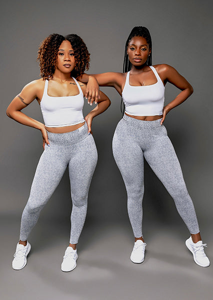 fit curvy beautiful black women with curly hair posing for a woman-owned black owned business wearing unique black white grey blue and teal activewear sets that feature back view of seamless scrunch butt high waist leggings and open back sports bra