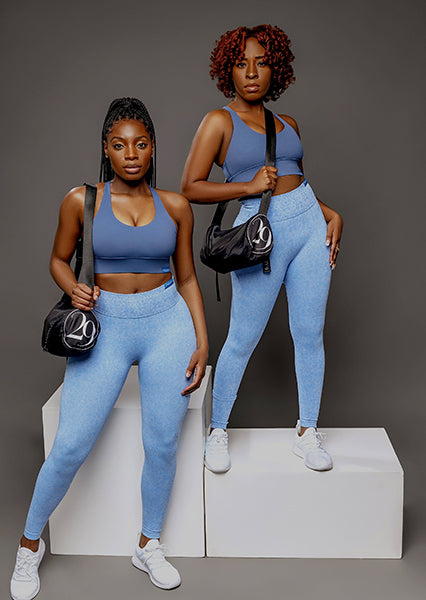 fit black women posing for a woman-owned black owned business wearing unique blue activewear sets that feature seamless scrunch butt high waist leggings and strappy sports bra and cute gym bag