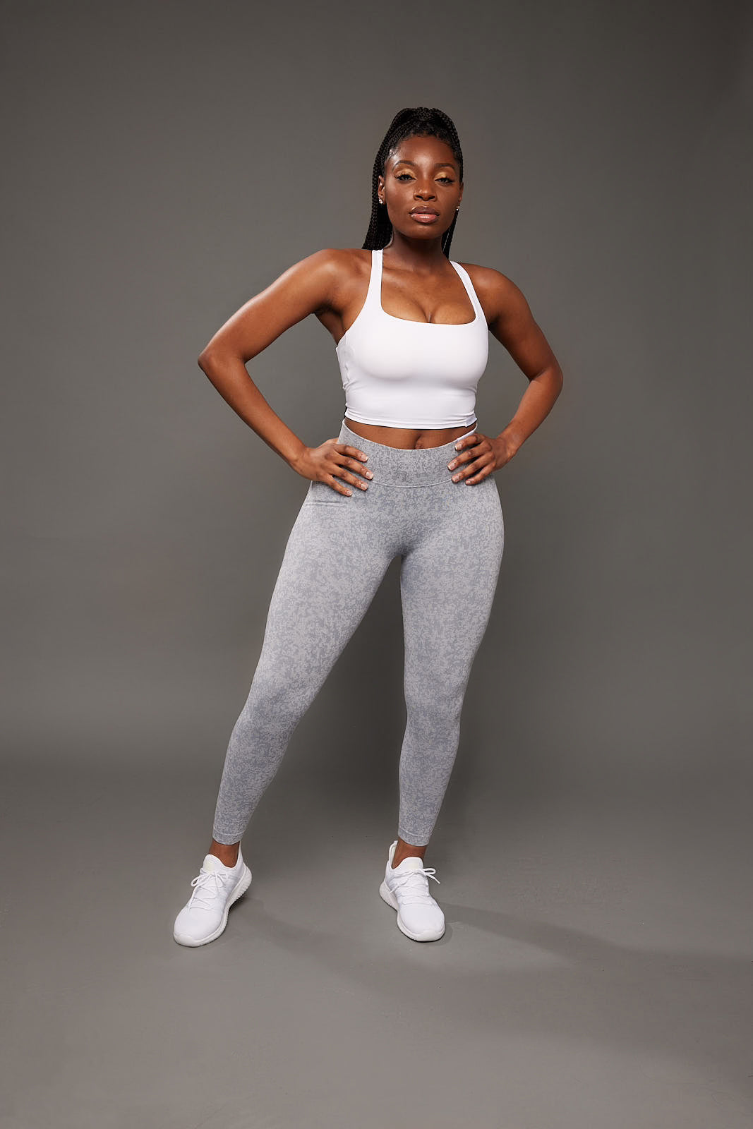 fit black woman posing for a woman-owned black owned business wearing unique white and grey activewear set that feature seamless scrunch butt high waist leggings and open back sports bra