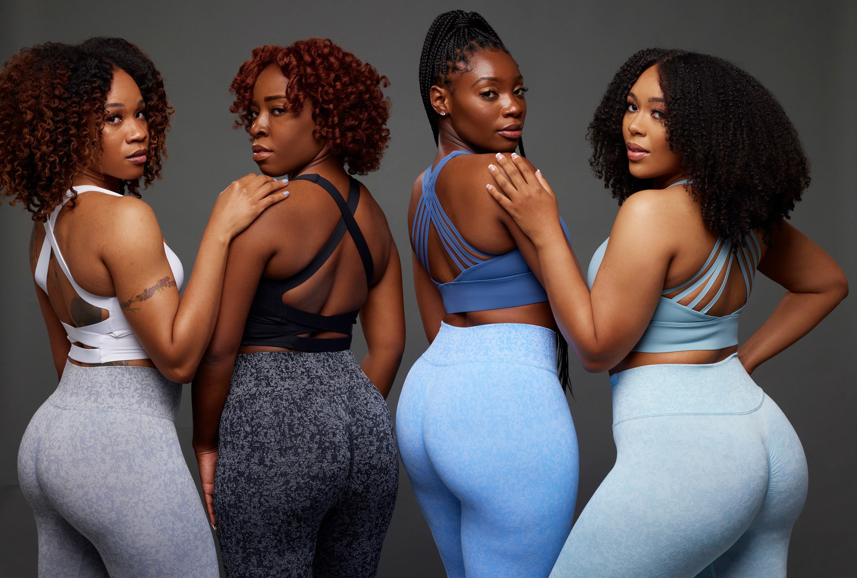 fit beautiful black women posing for a woman-owned black owned business wearing unique black white grey blue and teal activewear sets that feature back view of seamless scrunch butt high waist leggings and open back sports bra